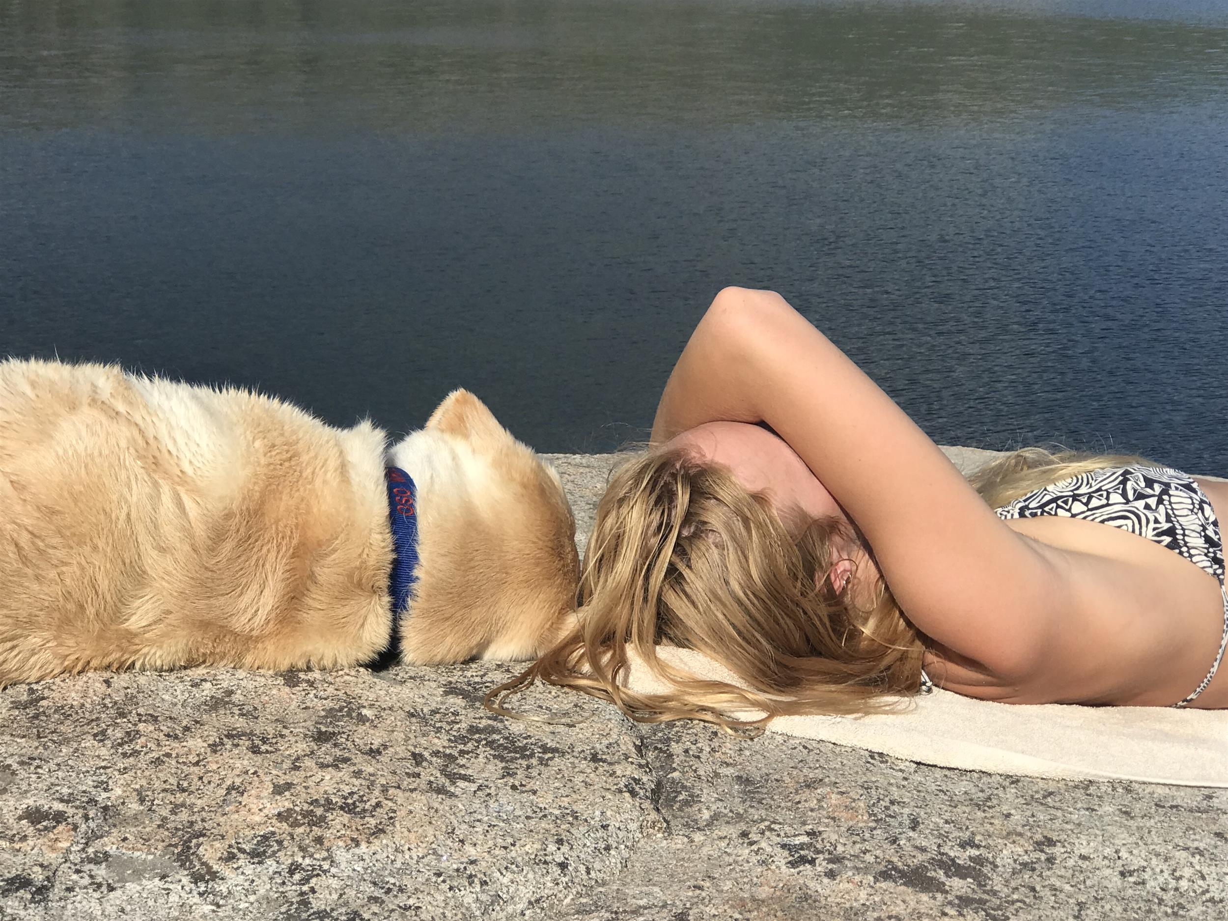 women and dog lounging on the beach